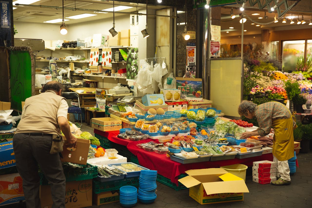 Arranged colorful containers with healthy vegetables and juicy fruits on lightened stall in market